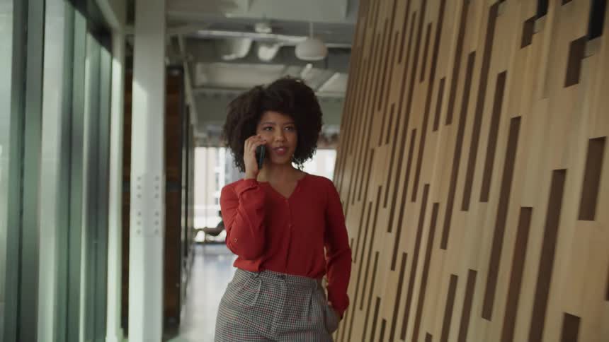 Young attractive woman talks on the phone while walking on a modern office