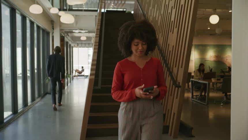 A woman walking down stairs looking at her phone and smiling