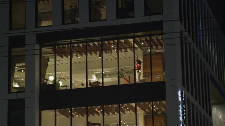 Businesswoman wearing red blouse and brown skirt talks on mobile phone in the office building