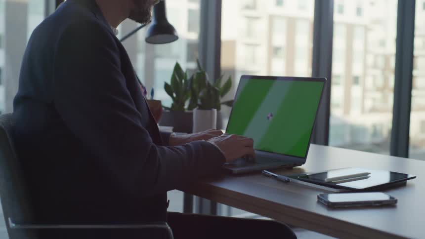 A man is sitting in his office at his computer desk