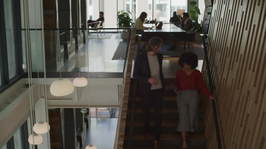 Businessman and businesswoman go downstairs in office building