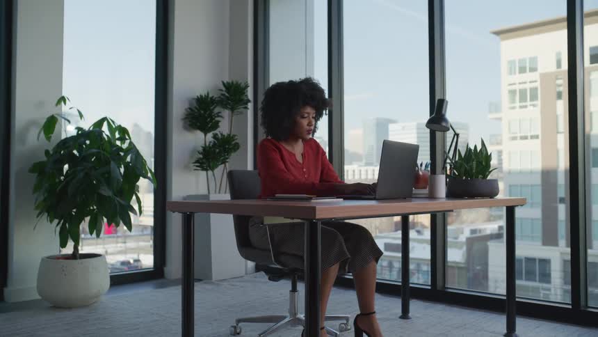 A woman types on a laptop in an office during the day