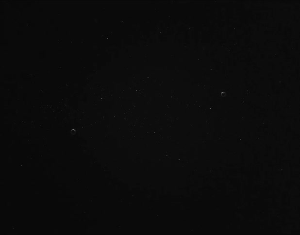 A dark screen with small white particles in the distance