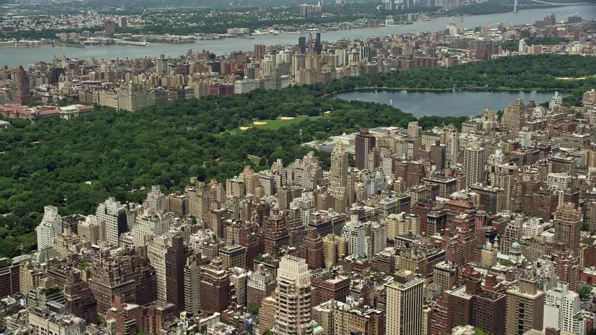 Aerial footage approaching Central Park from above Upper East Side apartment buildings in New York City during summertime