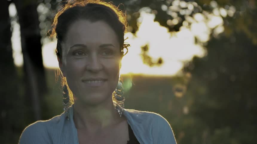 A woman smiles as the sun glares behind her