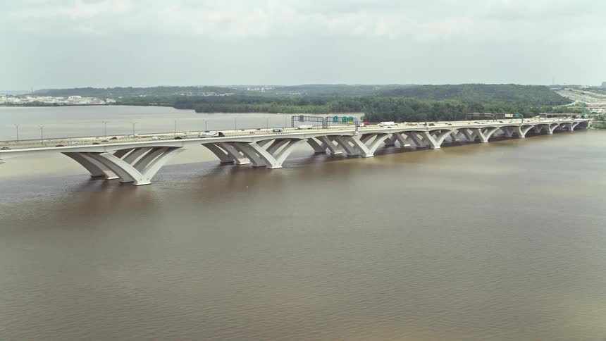Aerial footage of the Woodrow Wilson Memorial Bridge spanning the Potomac River during the daytime with light traffic and partly cloudy skies