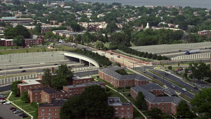 Aerial footage of slow traffic on Interstate 95 near an overpass and apartment buildings in Alexandria Virginia during daytime