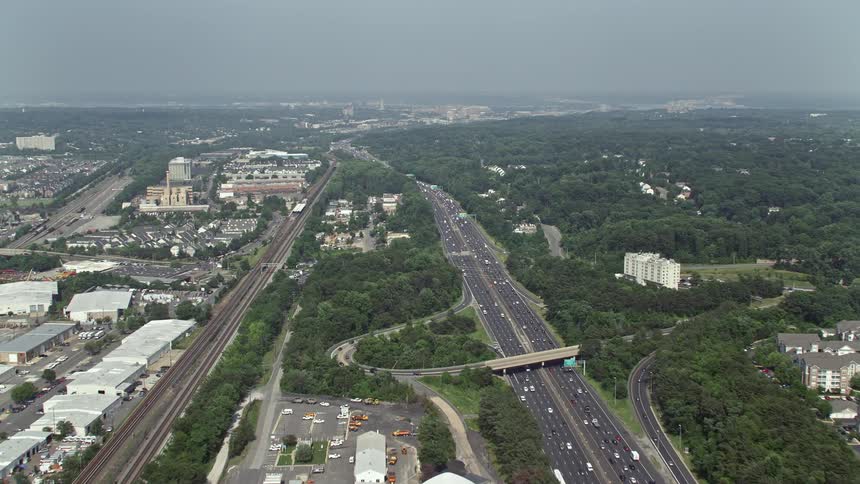 Aerial footage of light traffic on interstate 95 and industrial buildings by train tracks in Alexandria Virginia with a sunny and clear view