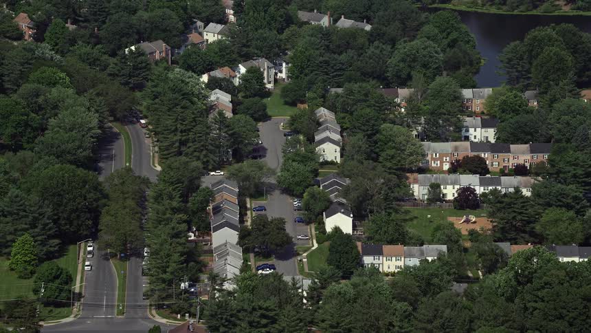 Approaching and tilting down to a row of residential houses and streets in Burke Virginia during a sunny summer day