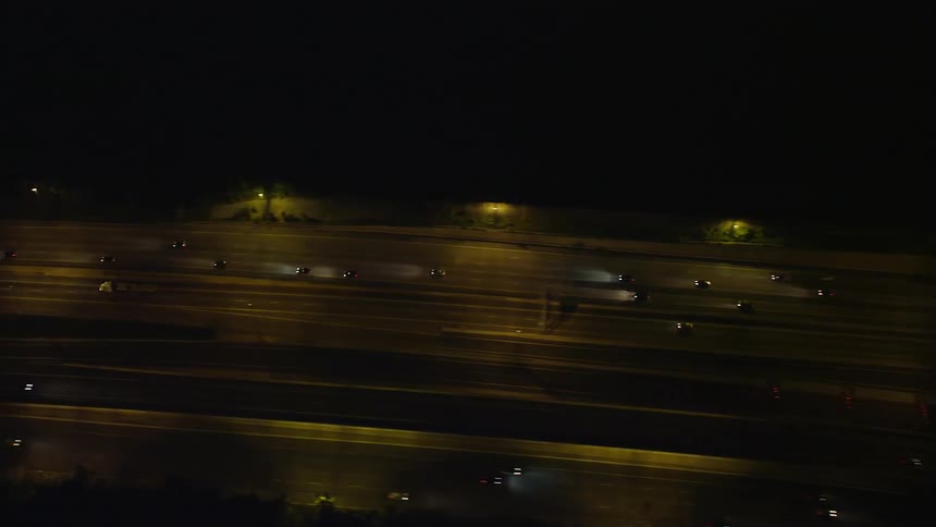 Aerial footage of cars and trucks flowing smoothly along Interstate 95 at night captured from a birds eye view in Alexandria Virginia