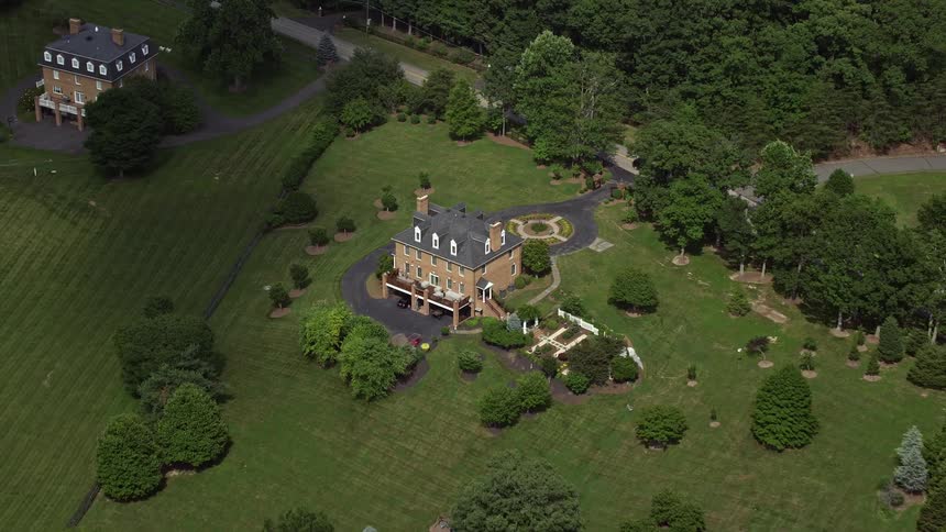 Approaching an isolated rustic mansion in Clifton Virginia via aerial footage and tilting down to capture the upscale home in a rural residential neighborhood