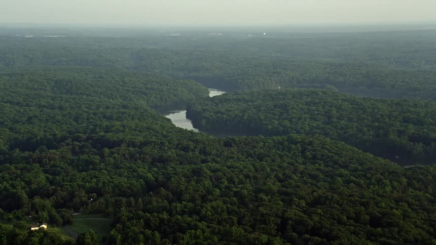 Aerial footage of Occoquan River winding through forest during sunset in Clifton Virginia