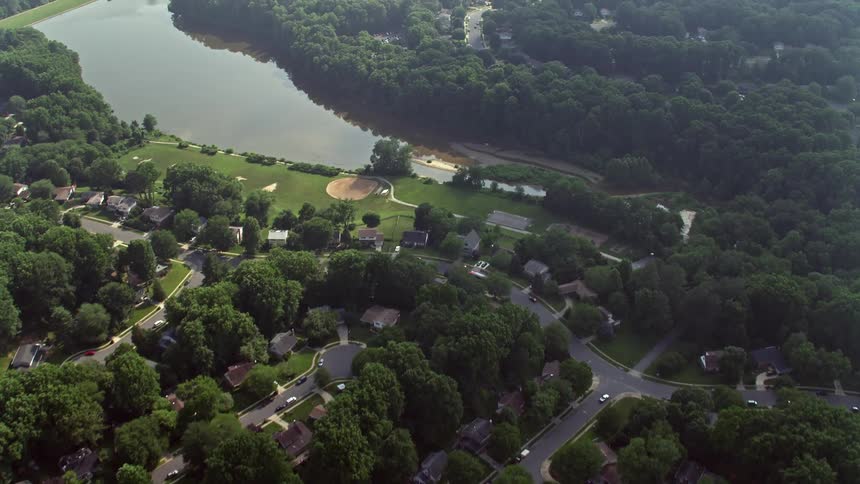 A birds eye view of suburban homes surrounding Lake Royal in Fairfax Virginia during a hazy day in summer
