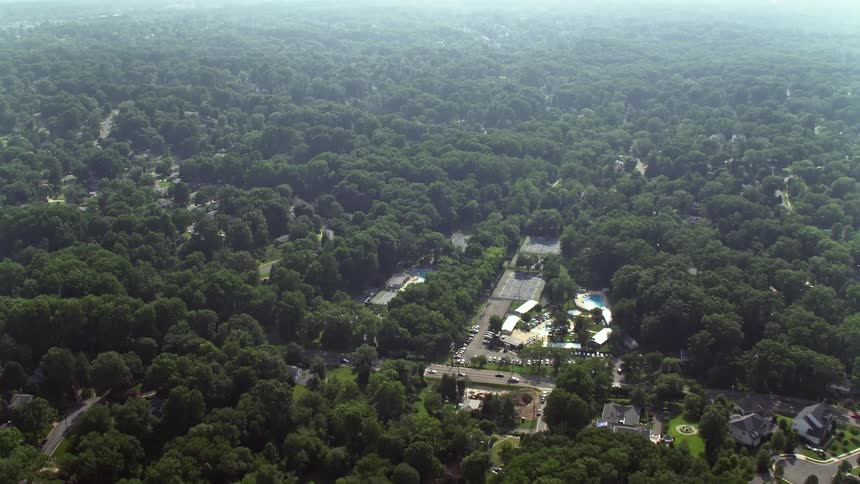 Aerial footage flying over tree-lined neighborhoods in Falls Church Virginia during the daytime