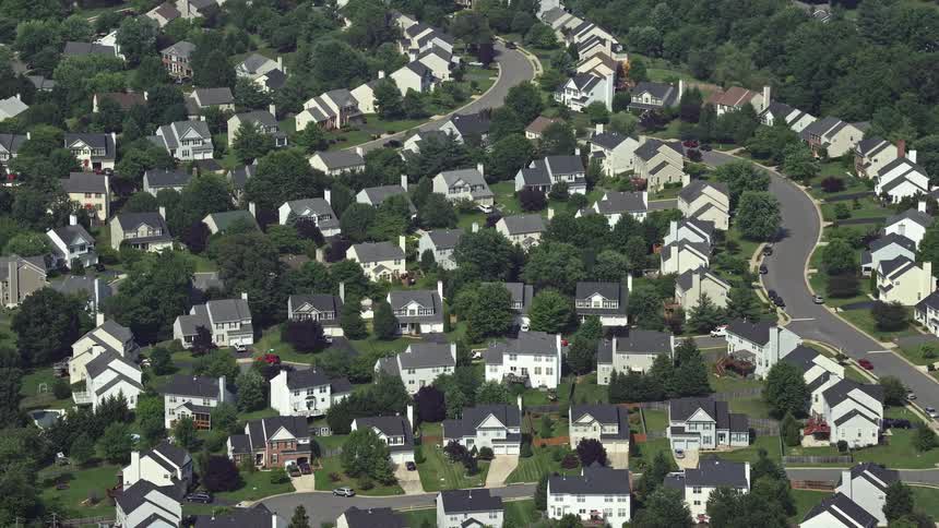 Approaching aerial footage tilts down to showcase suburban homes in Manassas Virginia on a sunny day