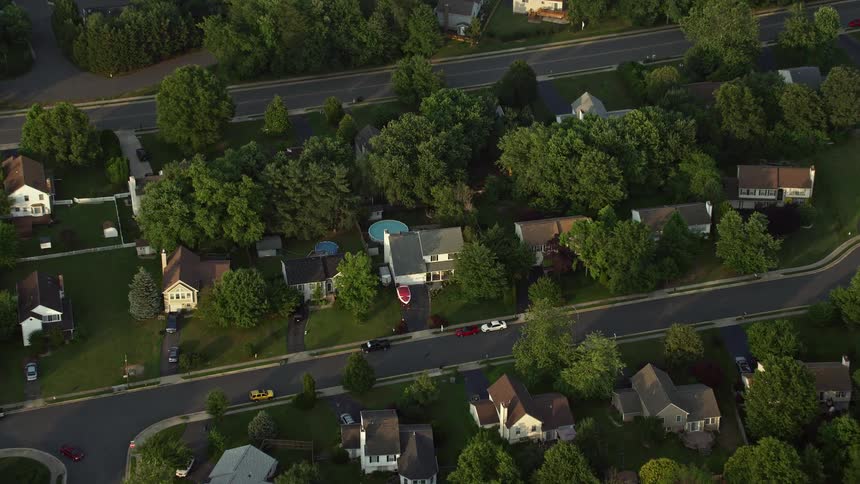 Aerial footage tilting down to birds eye view of suburban homes in Manassas Virginia during sunset