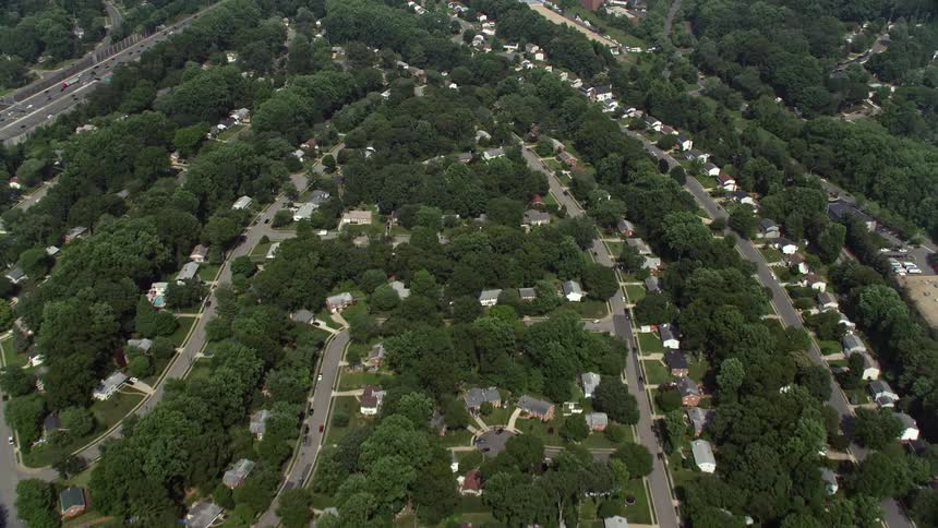 An aerial shot of suburban homes and tree-lined streets in Springfield Virginia reveals nearby retail centers and shopping centers