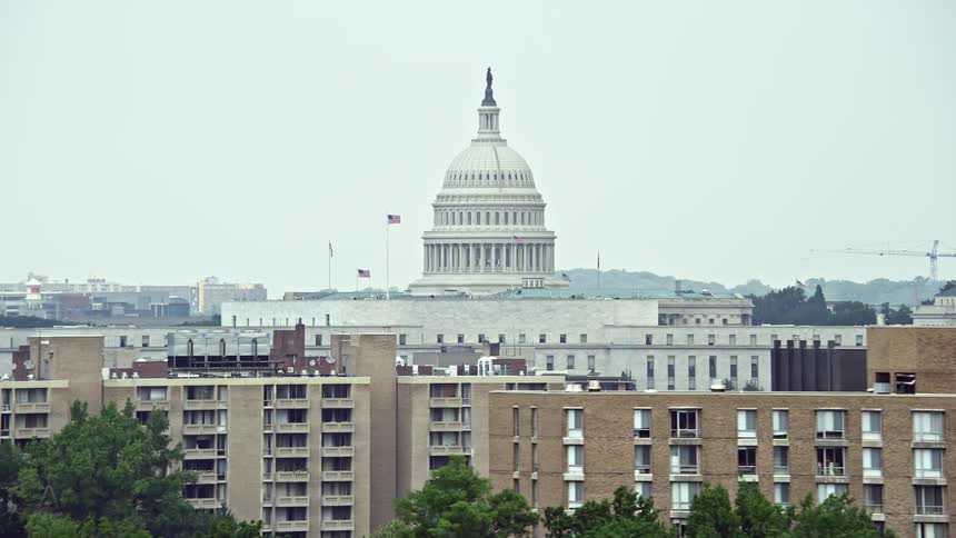 Aerial footage of the United States Capitol Dome surrounded by apartment buildings in Washington DC on a hazy summer day