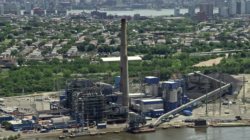 Aerial footage of the Hudson Generating Station in Jersey City New Jersey showcasing the industrial landscape and the smoke stacks during a sunny day of summer