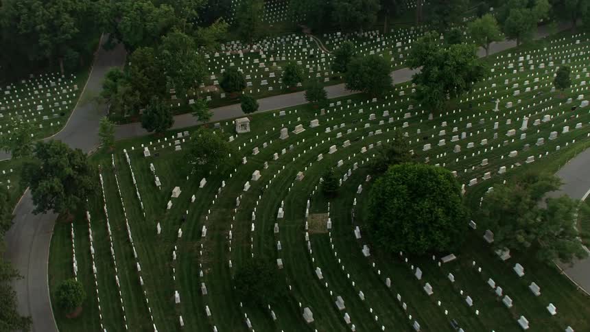 An aerial shot during twilight over Arlington National Cemetery Virginia tilting down to show the gravestones