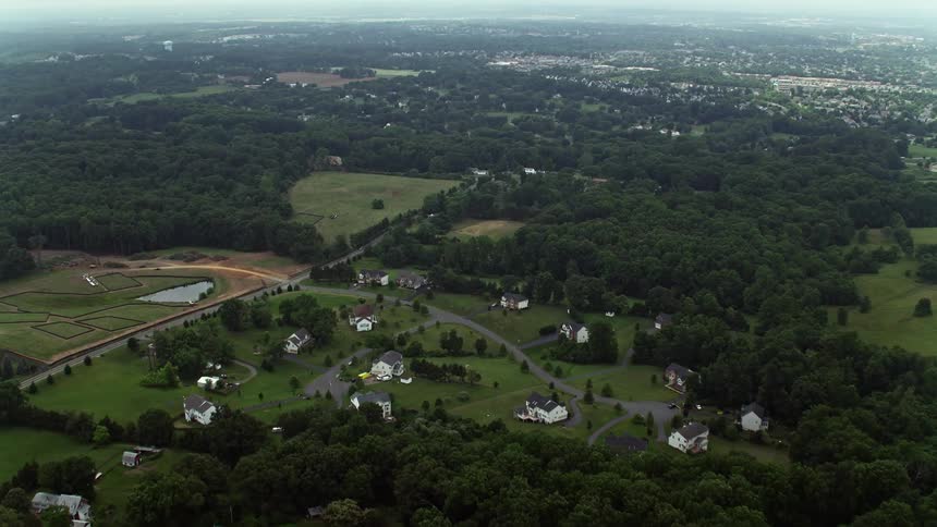 Aerial footage flying over a forest and approaching rural homes in a rustic neighborhood in Manassas Virginia during summer