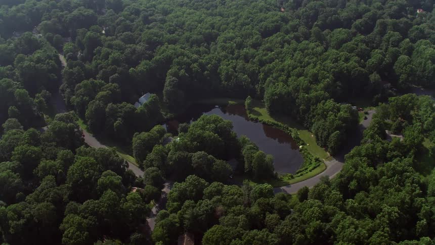 Aerial view of homes near a pond in rural Fairfax Station Virginia surrounded by forest