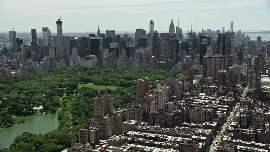 This is an aerial view of Midtown Manhattan skyscrapers and Central Park in New York City on a sunny day