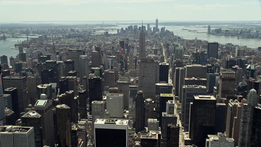 Flying over Midtown Manhattan skyscrapers to approach the iconic Empire State Building on a hazy day in New York City