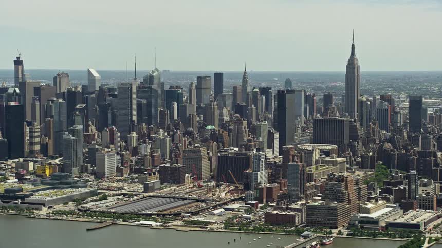 Aerial view of West Side Yard Hudson Yards and Midtown Manhattan skyscrapers with trains passing by over the Hudson River New York City