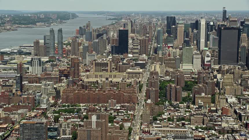 Aerial footage showcasing the towering skyscrapers of Hells Kitchen Midtown Manhattan alongside the Hudson River in New York City during the summer season
