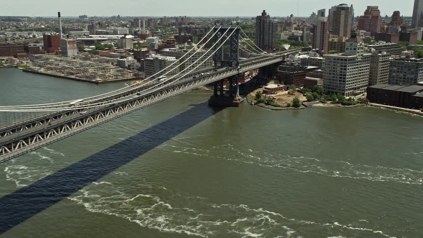 Aerial view of the famous Manhattan Bridge and its approach to Brooklyn with the skyline of sunny New York City visible in the background during daytime