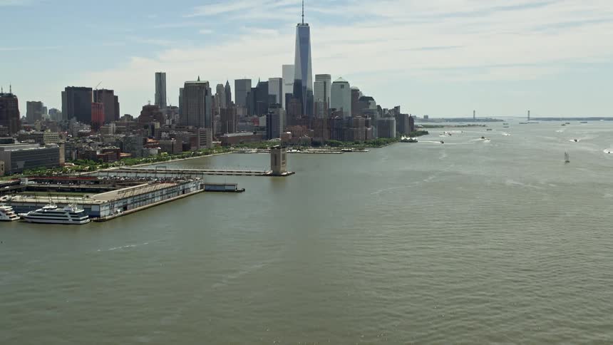 A stunning aerial view revealing the World Trade Center and Lower Manhattan skyline as the camera tilts up from the Hudson River