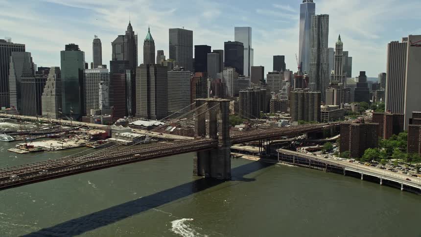 Approaching the iconic Brooklyn Bridge and Lower Manhattan skyline on a partly cloudy day in historical New York City