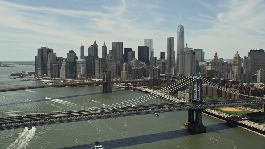 An aerial fly over of Manhattan Bridge approaching Brooklyn Bridge and the Lower Manhattan skyline in New York City