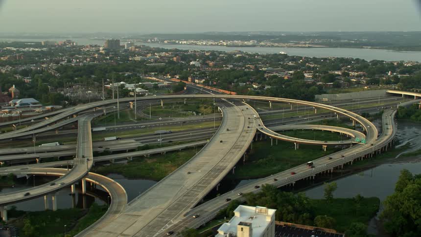 Aerial footage of the Richmond Highway interchange near Alexandria Virginia at sunset with light traffic driving down the highway overpass