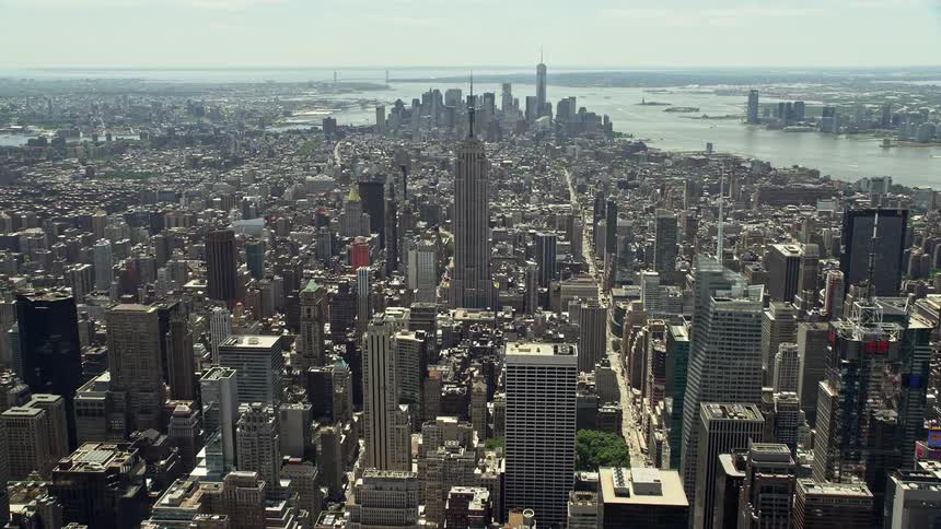 Flying over skyscrapers in Midtown Manhattan towards the historic landmark of the Empire State building in haze and haze New York City