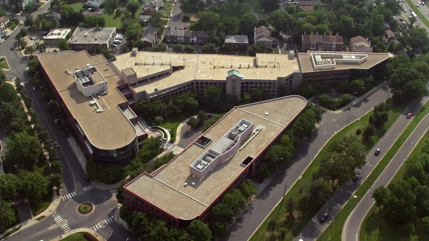 An aerial video clip of office buildings in Arlington Virginia during a sunny day approached and tilted down towards a single building