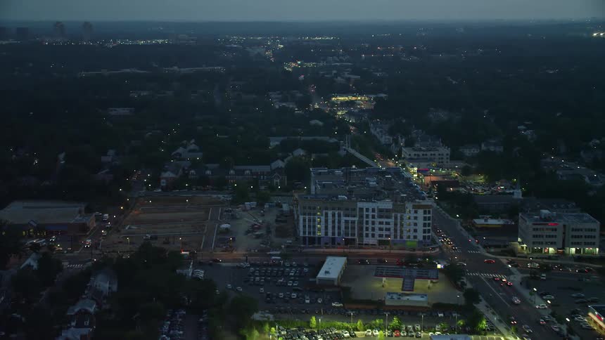 Aerial view of Columbia Pike in Arlington VA at night as cars drive past and buildings light up