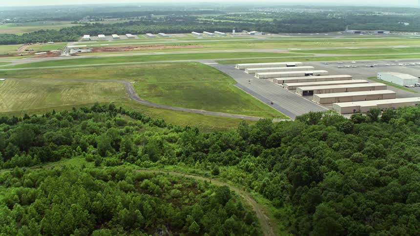 Aerial footage flying over Prince William Parkway intersection to approach Manassas Regional Airport capturing the view of rural hangars and an airplane