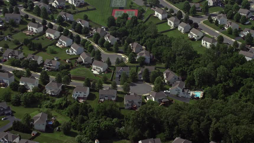 Aerial footage of a suburban neighborhood in Manassas Virginia with white homes and a roundabout at the end of a street