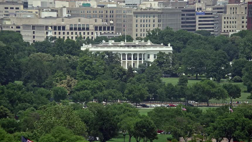 Aerial footage of the White House and South Lawn in Washington DC on a sunny day featuring the iconic structure and the South Lawn fountain