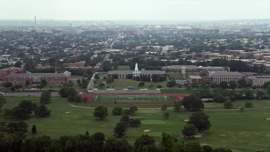 Aerial footage of schools and a football field in Washington DC with the Washington Monument and United States Capitol in the background