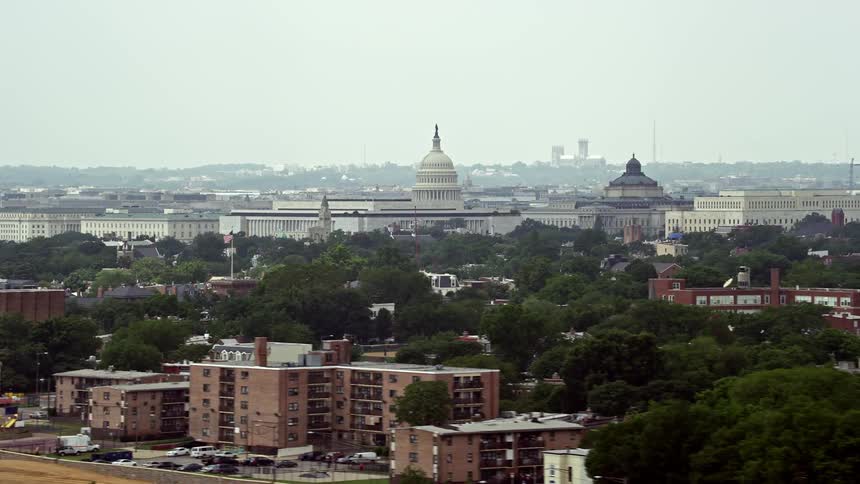 Aerial footage of the United States Capitol and Thomas Jefferson Building Domes in Washington DC on a hazy day showcasing the iconic government buildings and landmarks from afar