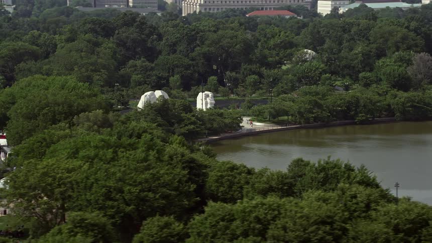 Aerial view flying by trees to reveal Martin Luther King Jr National Memorial in Washington DC during daytime