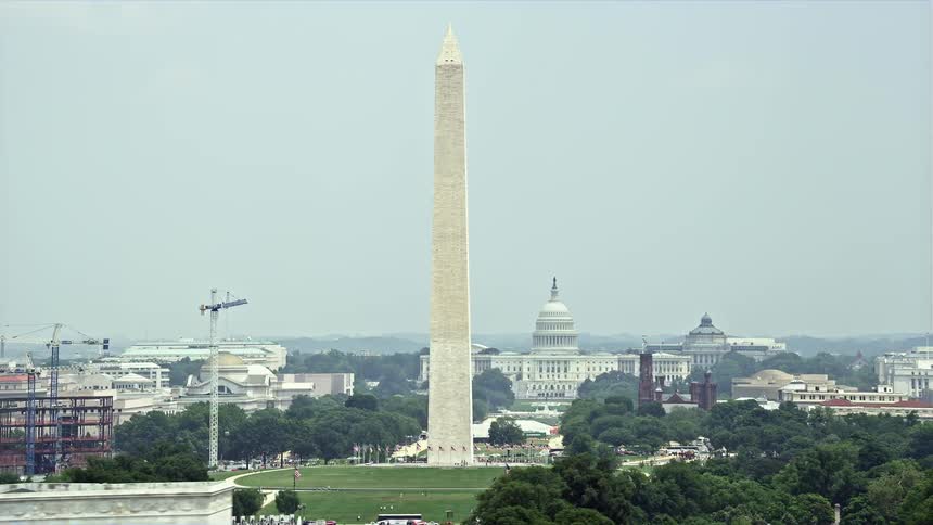 Aerial footage of the Washington Monument and Capitol Building in Washington DC on a hazy daytime