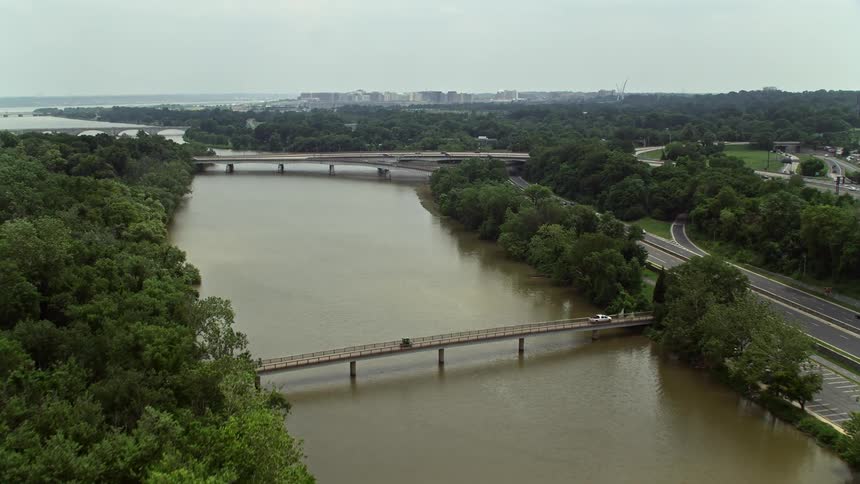 Aerial view of a footbridge leading to the Theodore Roosevelt Memorial Bridge in Washington DC with a hazy cityscape in the background