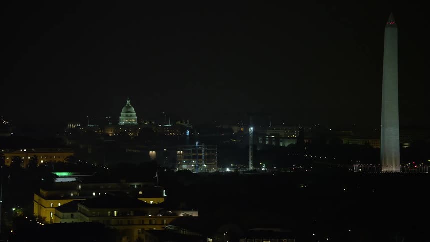 Aerial footage at night of the United States Capitol dome construction cranes and the Washington Monument in Washington DC