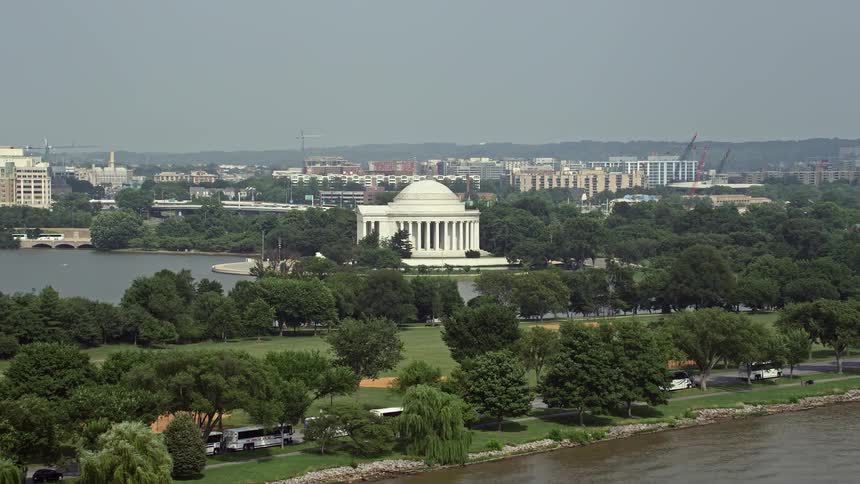 Approaching the iconic Thomas Jefferson Memorial from the sunny Potomac River captured in aerial footage during a beautiful day in Washington DC