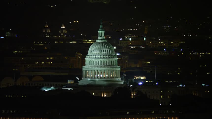 Aerial footage at night of the iconic United States Capitol and the Thomas Jefferson Building domes in Washington DC showing a clear beautiful summer sky