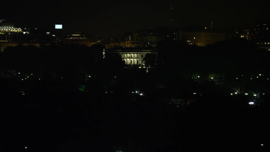 A stunning night aerial view of The White House Washington DC glowing in the distance as a clear sky and lightning set the scene